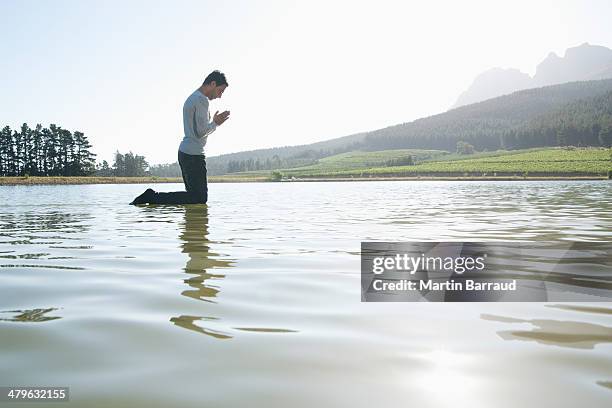man kneeling on water praying - dopen stockfoto's en -beelden