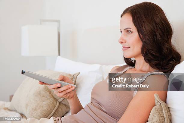 woman sitting in bed with the television remote - changing channels stock pictures, royalty-free photos & images