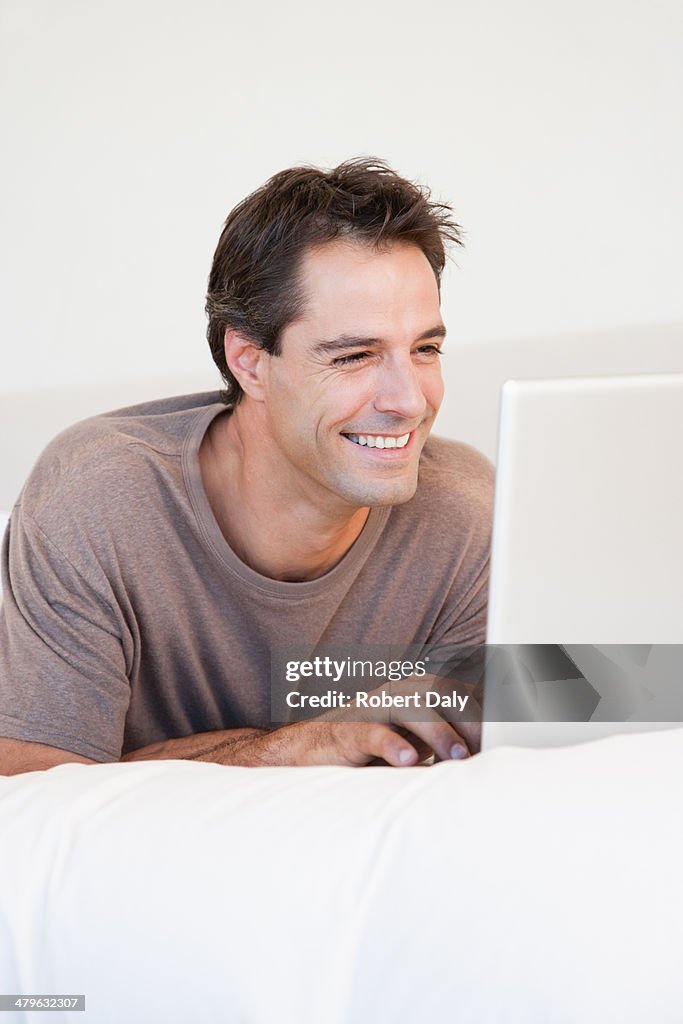 Man lying in bed using a laptop