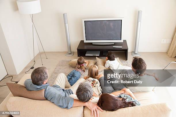 una joven familia con abuelos viendo la televisión - familia viendo la television fotografías e imágenes de stock