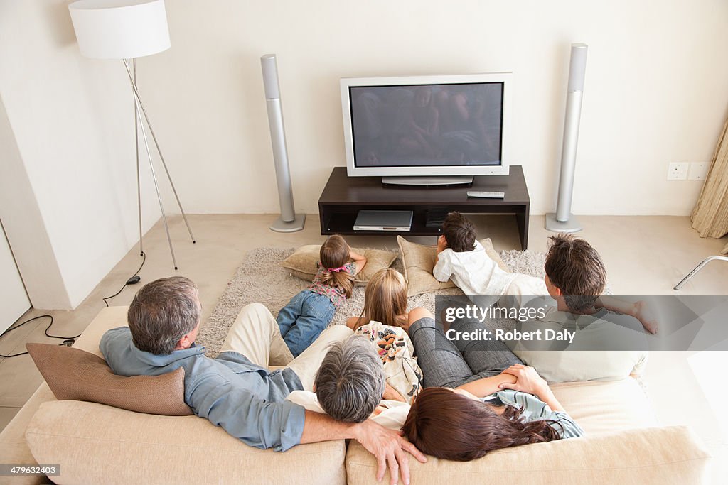 A young family watching television with grandparents