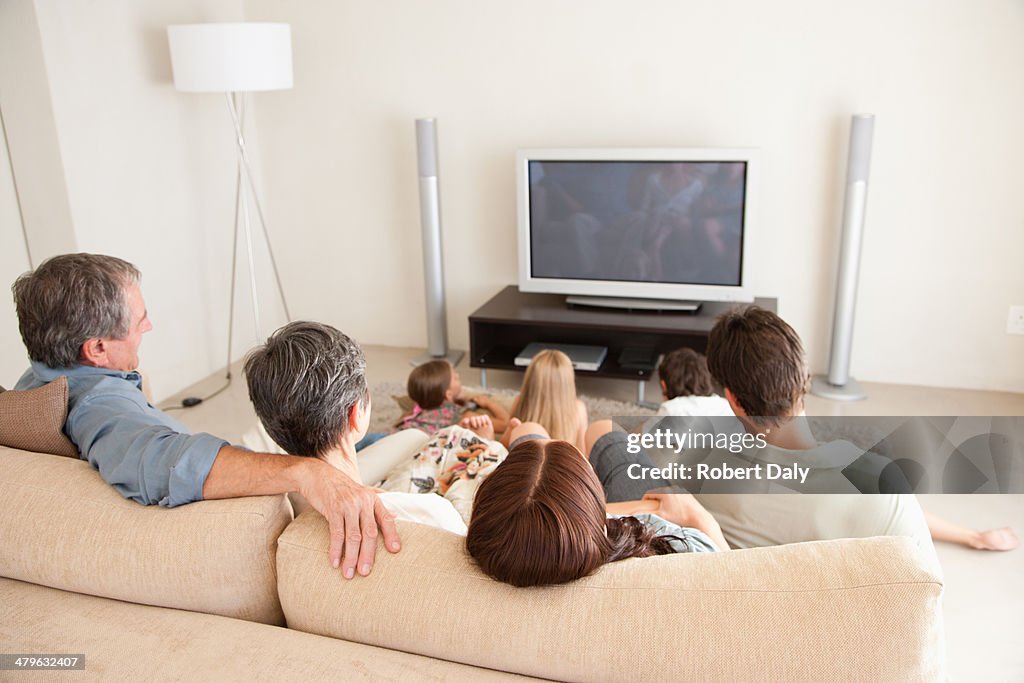 A young family watching television with grandparents