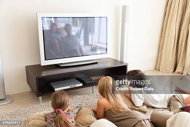 una joven familia viendo la televisión - familia viendo la television fotografías e imágenes de stock