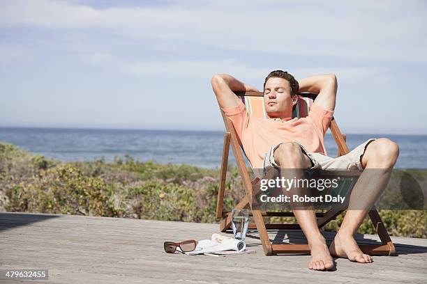 man relaxing in a lounge chair - man mid 20s warm stock pictures, royalty-free photos & images