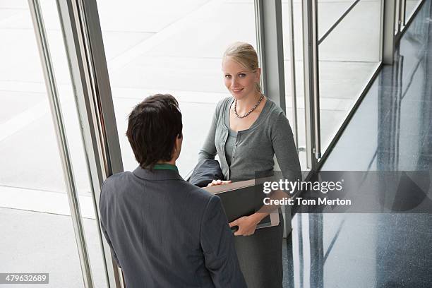 co-workers talking in office lobby - man talking to camera stock pictures, royalty-free photos & images