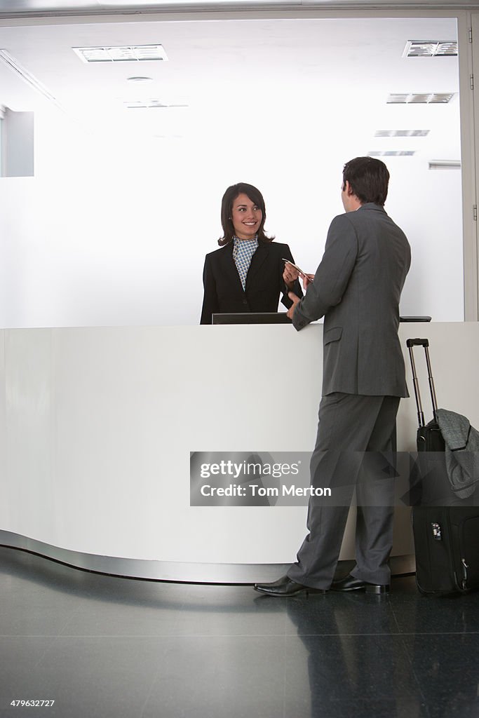 Businesswoman greeting businessman at reception desk