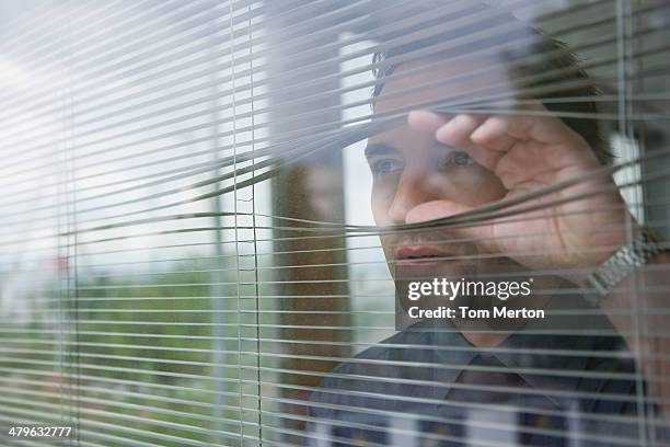 un homme d'affaires regardant par la fenêtre de bureau - homme inquiet photos et images de collection