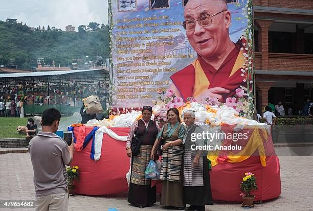 Tibetan takes pictures in front of the portrait of their spiritual leader 14th Dalai Lama during his 80th birthday celebration in Kathmandu, July 6,...
