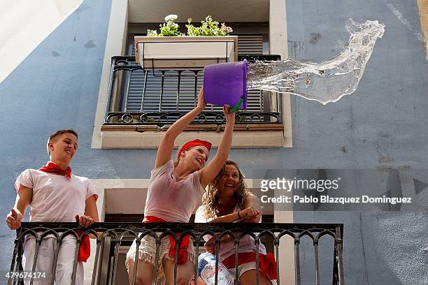 Revellers throw a bucket of water from a balcony to the crowd during the opening day or 'Chupinazo' of the San Fermin Running of the Bulls fiesta on...