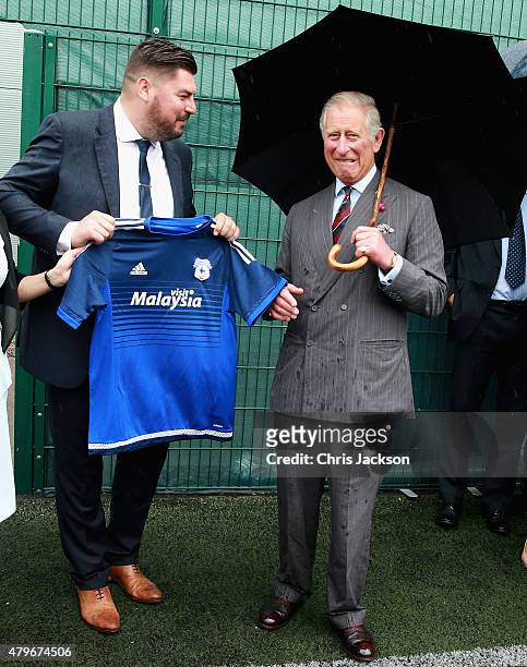 Prince Charles, Prince of Wales is presented with a Cardiff City football shirt after meeting young offenders taking part in a 'Get Started with...