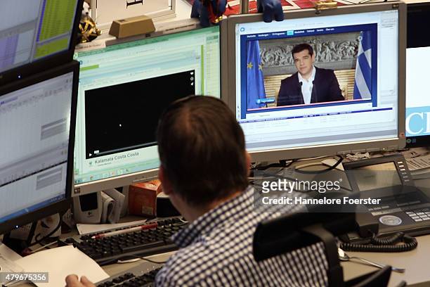 Trader on the trading floor of the Frankfurt Stock Exchange as a monitor shows Alexis Tsipras at the day after the 'NO' vote in the Greek referendum...