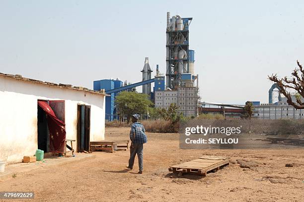 Man walks towards a house near the Dangote Industries cement plant under construction in Pout, some 50 km from Dakar, on February 6, 2014. The...
