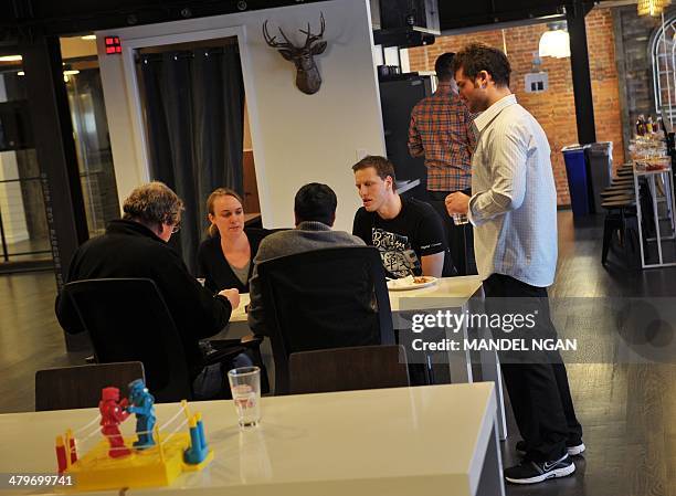 People gather around a table during a break at the "WeWork" co-operative co-working space on March 13, 2013 in Washington, DC.In a large...