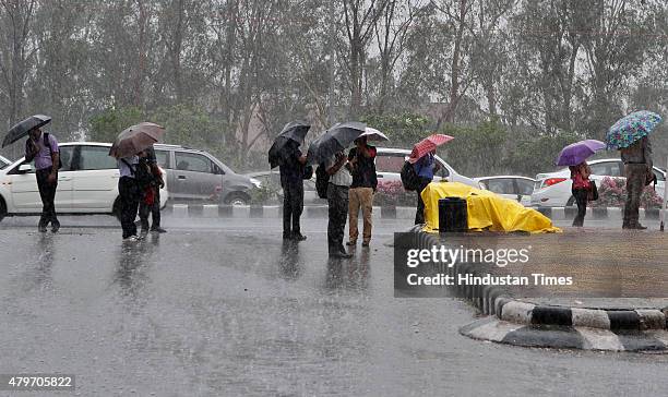 People use umbrella to protect themselves from heavy rainfall on July 6, 2015 in New Delhi, India. The city received heavy rains in the morning and...