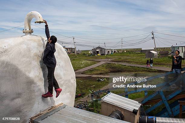 Boys play on storage tanks for fuel on July 5, 2015 in Newtok, Alaska. Newtok, which is having to relocate due to melting permafrost and rapid...