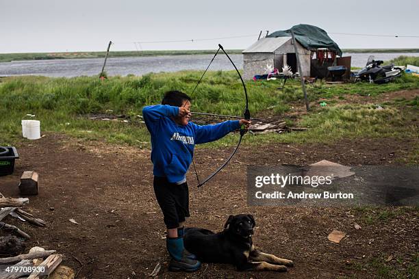 Thaddeus John, age 8, plays with a bow and arrow on July 5, 2015 in Newtok, Alaska. Newtok, which has a population of approximately of 375 ethnically...