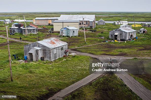 People walk down the elevated, raised wooden sidewalks - created so people don't sink into the melting permafrost - on July 5, 2015 in Newtok,...