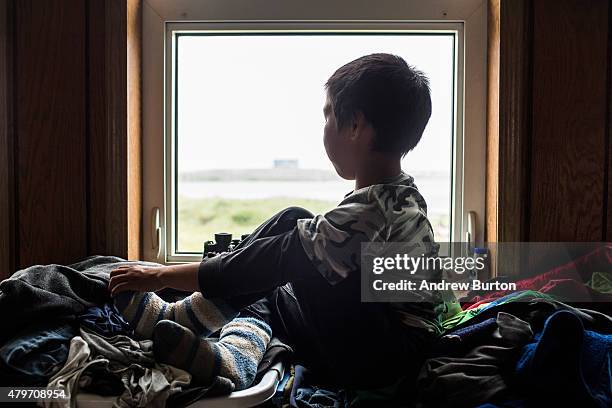 Samuel John, age 8, looks out his window across the tundra on July 5, 2015 in Newtok, Alaska. Newtok, which has a population of approximately of 375...