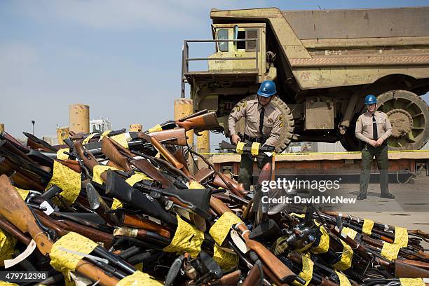 Los Angeles County Sheriff Jim McDonnell throws guns into a pile during the destruction of approximately 3,400 guns and other weapons at the Los...