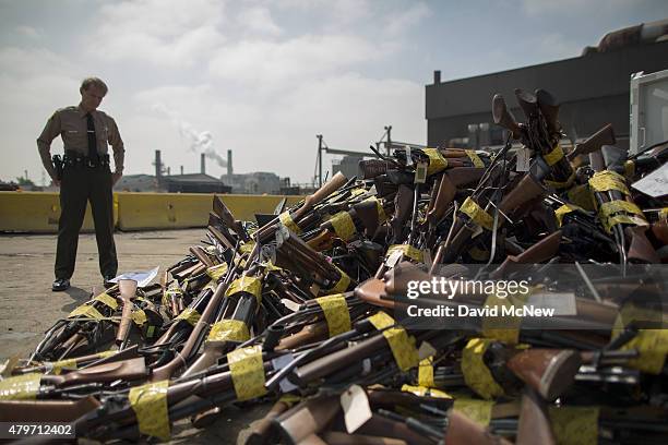 Los Angeles County Sheriffs deputy looks at a pile of guns during the destruction of approximately 3,400 guns and other weapons at the Los Angeles...