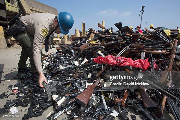 Los Angeles County Sheriffs deputy looks at guns during the destruction of approximately 3,400 guns and other weapons at the Los Angeles County...