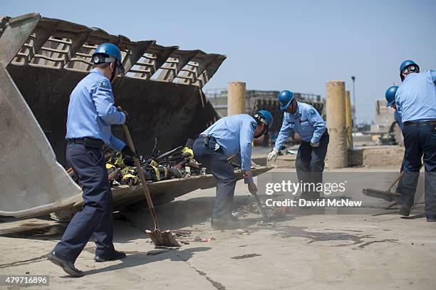Los Angeles County Sheriffs deputies load guns into a front loader during the destruction of approximately 3,400 guns and other weapons at the Los...