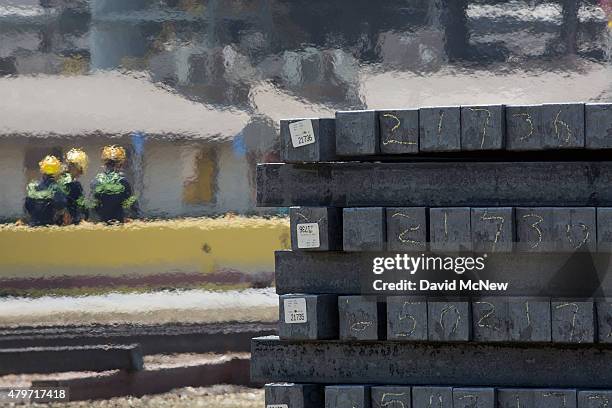 Workers walk past stacks 1,800-degree billets, cooling from 3,000 degrees when emerging from the mill, during the destruction of approximately 3,400...