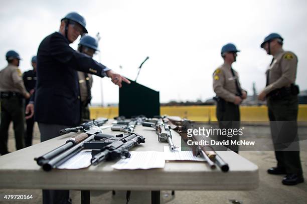 Officials look at confiscated guns prior to the destruction of approximately 3,400 guns and other weapons at the Los Angeles County Sheriffs' 22nd...