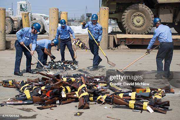 Los Angeles County Sheriffs deputies pick up guns during the destruction of approximately 3,400 guns and other weapons at the Los Angeles County...