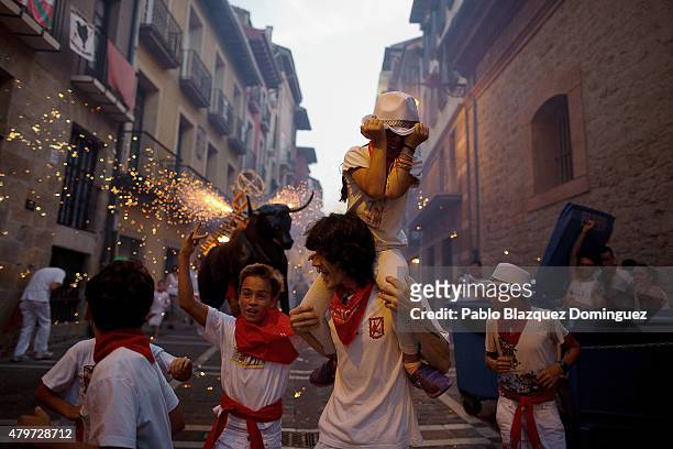 People and children are chased by the 'Toro de Fuego' as it runs throught the streets during the opening day of the San Fermin Running of the Bulls...
