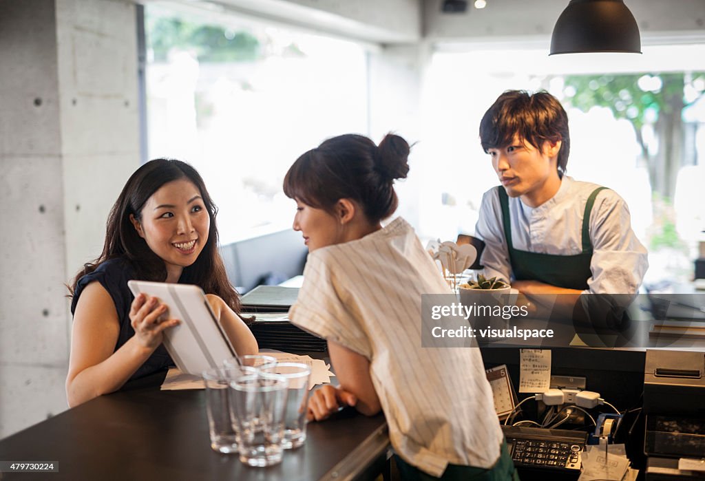 Young asian cafe owner using tablet computer