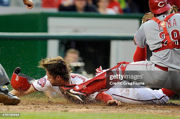 Matt den Dekker of the Washington Nationals scores on a wild pitch ahead of the tag of Brayan Pena of the Cincinnati Reds in the third inning at...