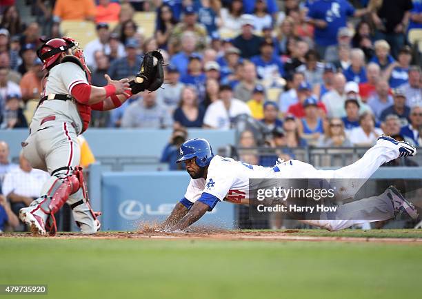 Howie Kendrick of the Los Angeles Dodgers slides ahead of a tag from Carlos Ruiz of the Philadelphia Phillies to score on a sacrifice fly taking a...