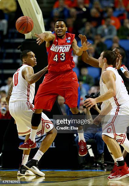 Vee Sanford of the Dayton Flyers passes the ball as LaQuinton Ross of the Ohio State Buckeyes defends during the second round of the 2014 NCAA Men's...