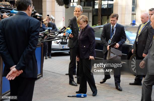 German Chancellor Angela Merkel looks at a reporter's microphone that fell on the ground upon her arrival at the EU headquarters in Brussels on March...