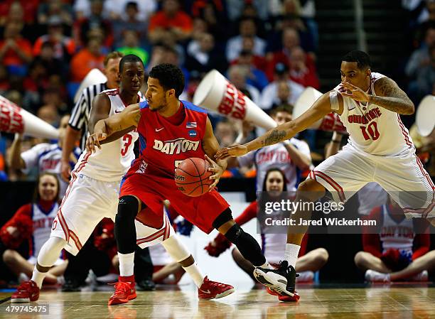 Devin Oliver of the Dayton Flyers controls the ball as LaQuinton Ross and Shannon Scott of the Ohio State Buckeyes defend during the second round of...