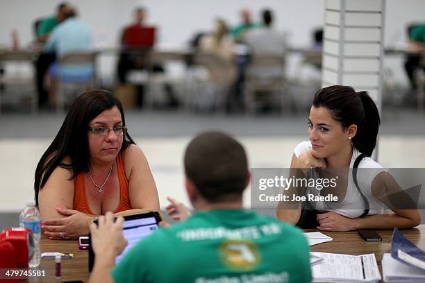 Lidice Bacallao andYislaine Diaz sit with Amaury Garcia an insurance agent from Sunshine Life and Health Advisors as they purchase individual health...