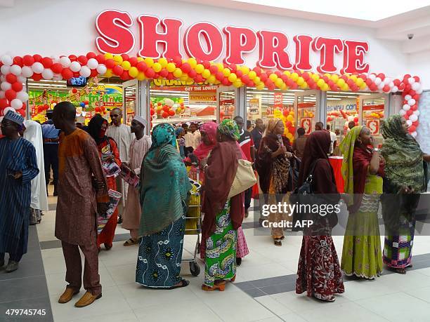 Shoppers stand outside the main entrance of the new South African retail giant Shoprite outlet in Kano, northern Nigeria, on March 20, 2014. South...