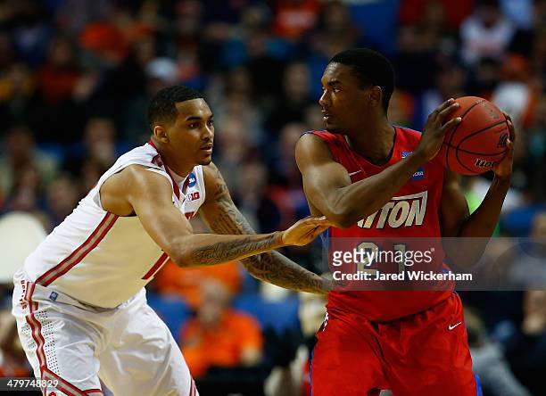 Dyshawn Pierre of the Dayton Flyers looks to pass as LaQuinton Ross of the Ohio State Buckeyes defends during the second round of the 2014 NCAA Men's...