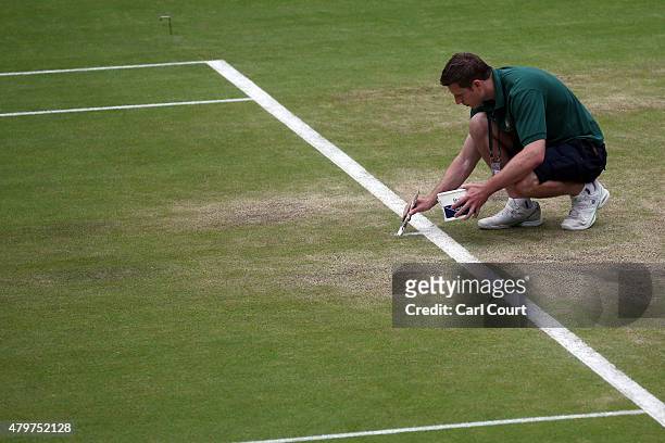 Member of ground staff hand paints a line on Centre Court ahead of play on day 8 of the Wimbledon Lawn Tennis Championships at the All England Lawn...
