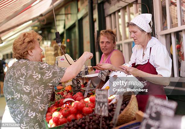 Customer pays a market stall holder with a euro bank note and some coins on at Naschmarkt in Vienna, Austria, on Friday, July 3, 2015. Austria broke...