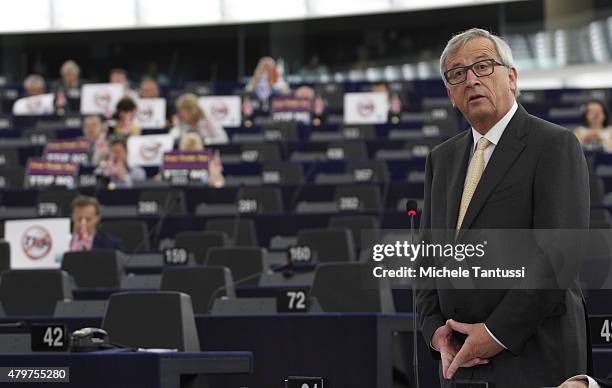 Jean-Claude Juncker, President of the European Commission, speaks as members of the right wing section of the parliament hold placards agains the...