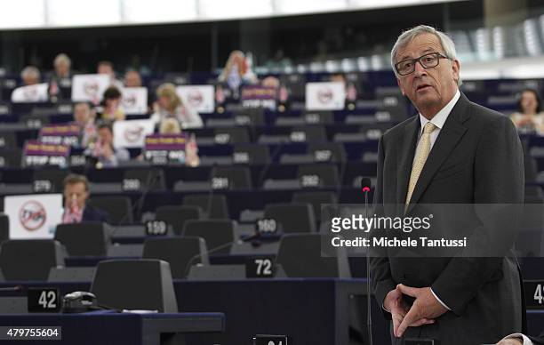 Jean-Claude Juncker, President of the European Commission, speaks as members of the right wing section of the parliament hold placards agains the...