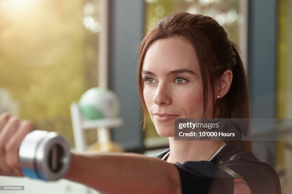 Woman in a gym holding dumbbell out