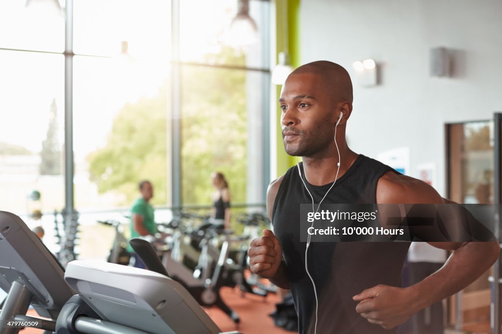 Man in a gym running on a treadmill.