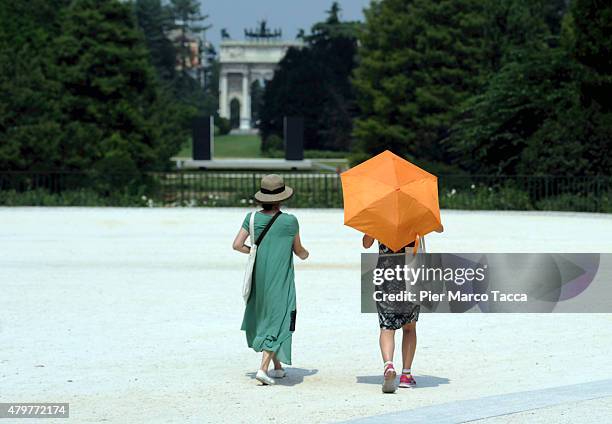 Woman takes shelter from the sun with an umbrella in the gardens of the castle Sforzesco, to cool off from the heat on July 7, 2015 in Milan, Italy....