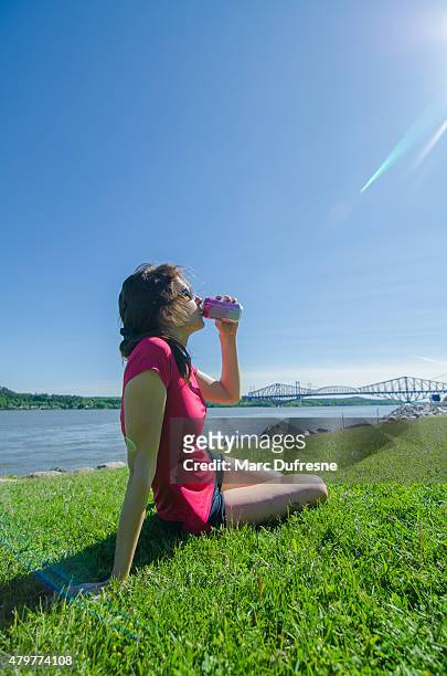 woman drinking juice while sitting on grass - blank can stockfoto's en -beelden