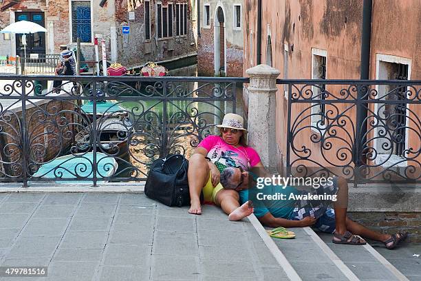 Two tourists rest exausted from the heat and the sun on a bridge on July 7, 2015 in Venice, Italy. An intense heatwave is sweeping across many...