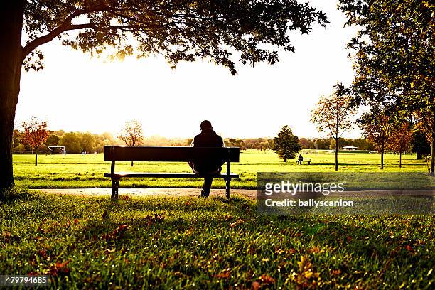 man sitting on park bench - banco de parque imagens e fotografias de stock