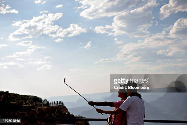 Visitors talk a photograph while using a selfie stick on Mather Point at Grand Canyon National Park in Grand Canyon, Arizona, U.S., on Wednesday,...